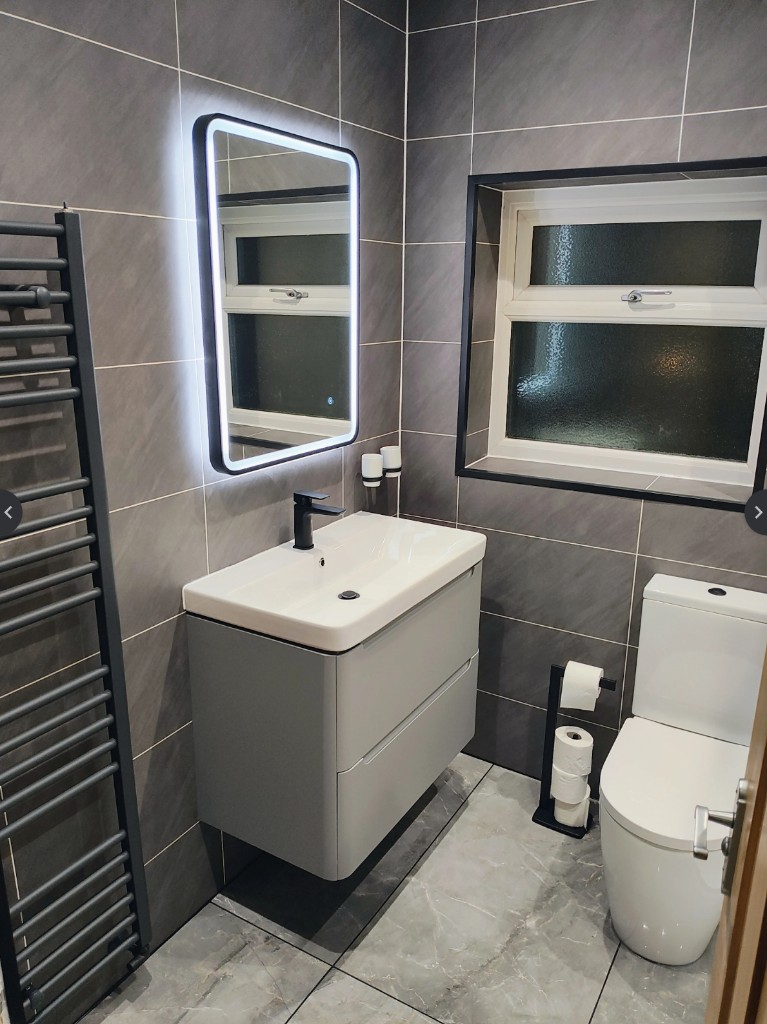 Bathroom after renovation, Sunderland — modern dark grey tiles, wall-hung vanity and backlit mirror